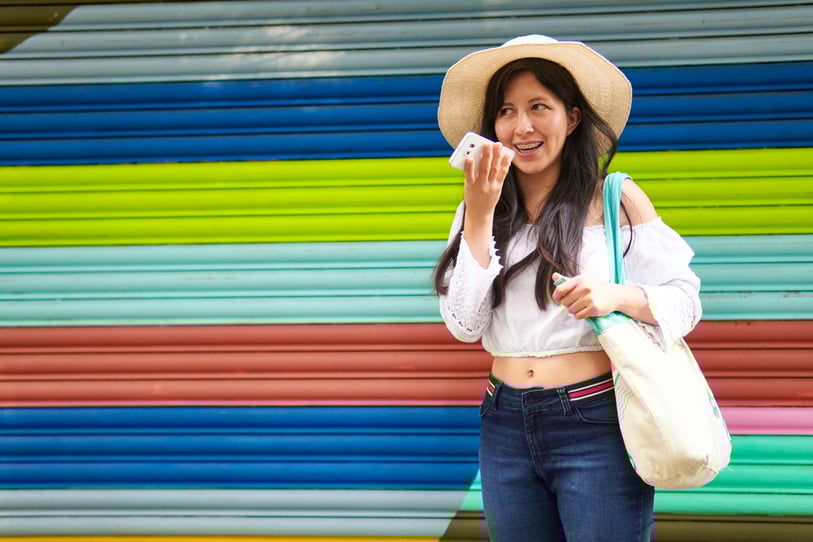 A woman in front of a colorful wall showing voice search and AI-powered search with generative engines to demonstrate the need for GEO or generative engine optimization in marketing